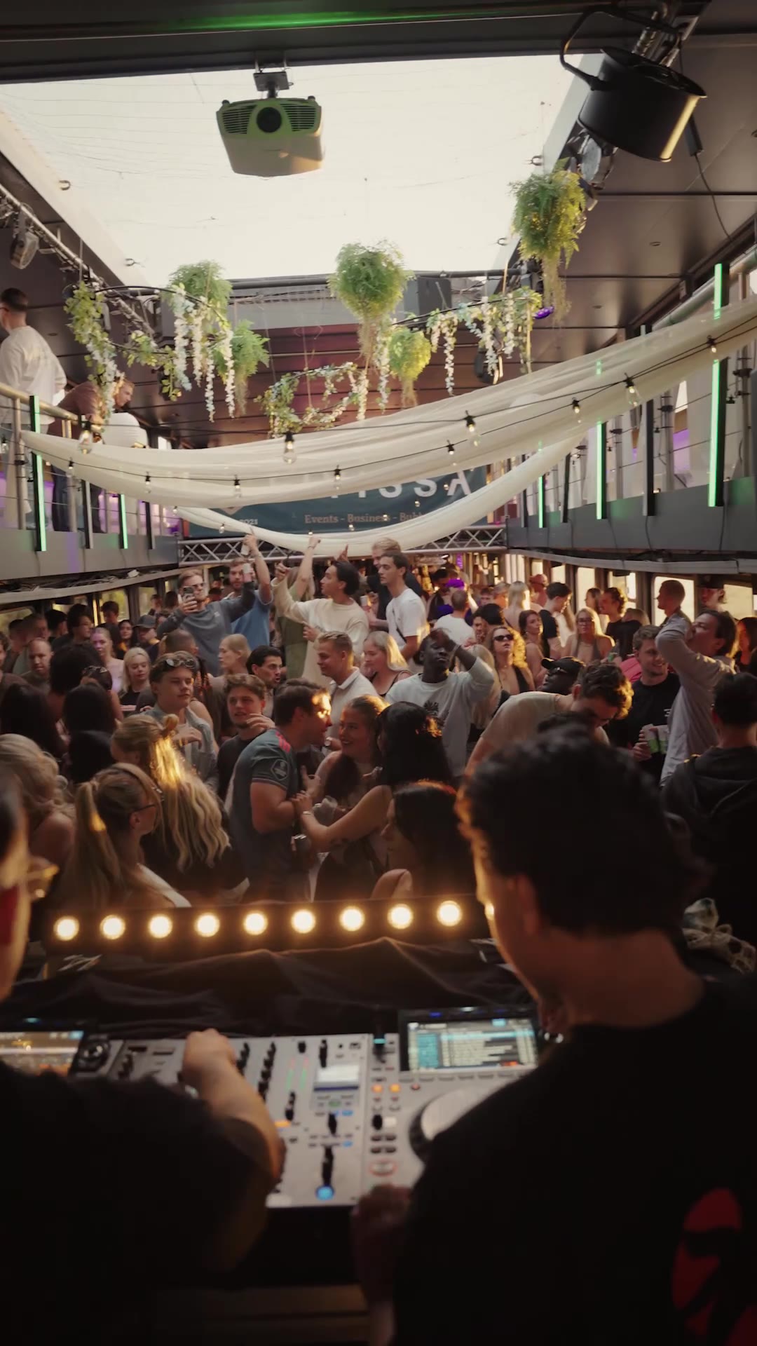 Friends gathered around the DJ beneath warm draped lights on the Sunset Cruise